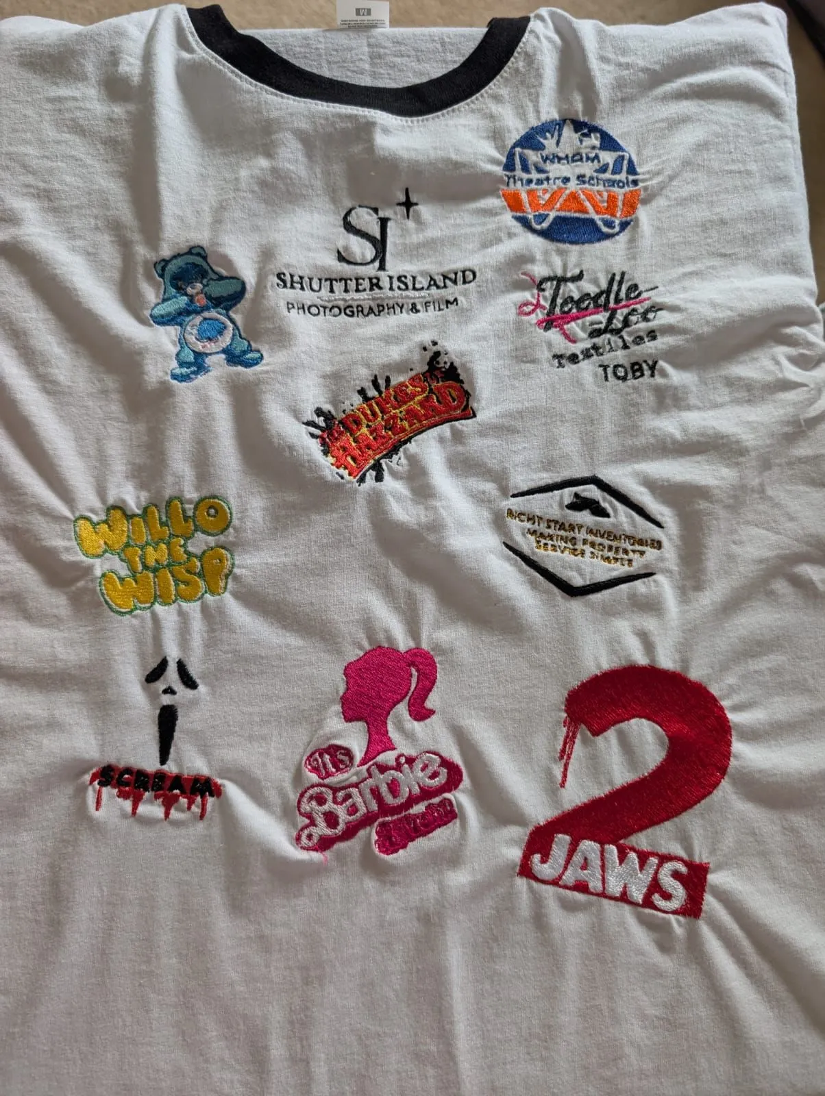 White T-shirt covered in a colourful collection of embroidered logos and character designs