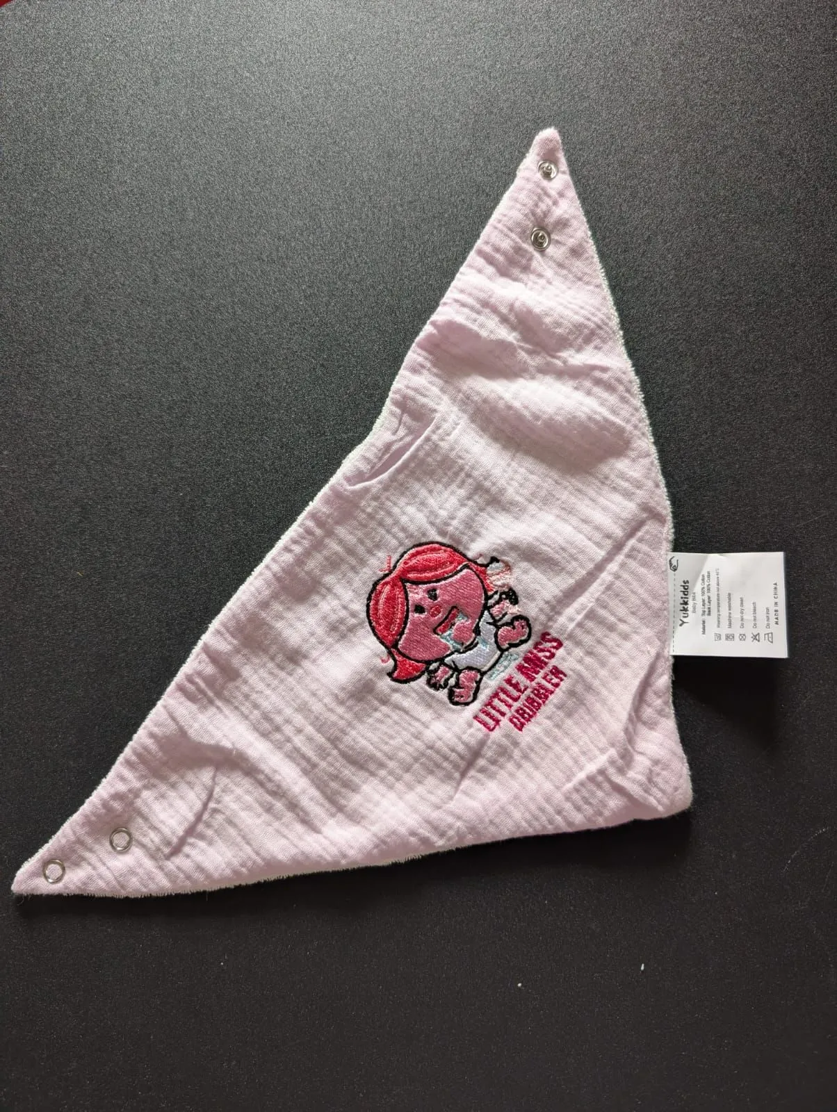 Pink baby bib with a colourful embroidered cartoon character and lettering