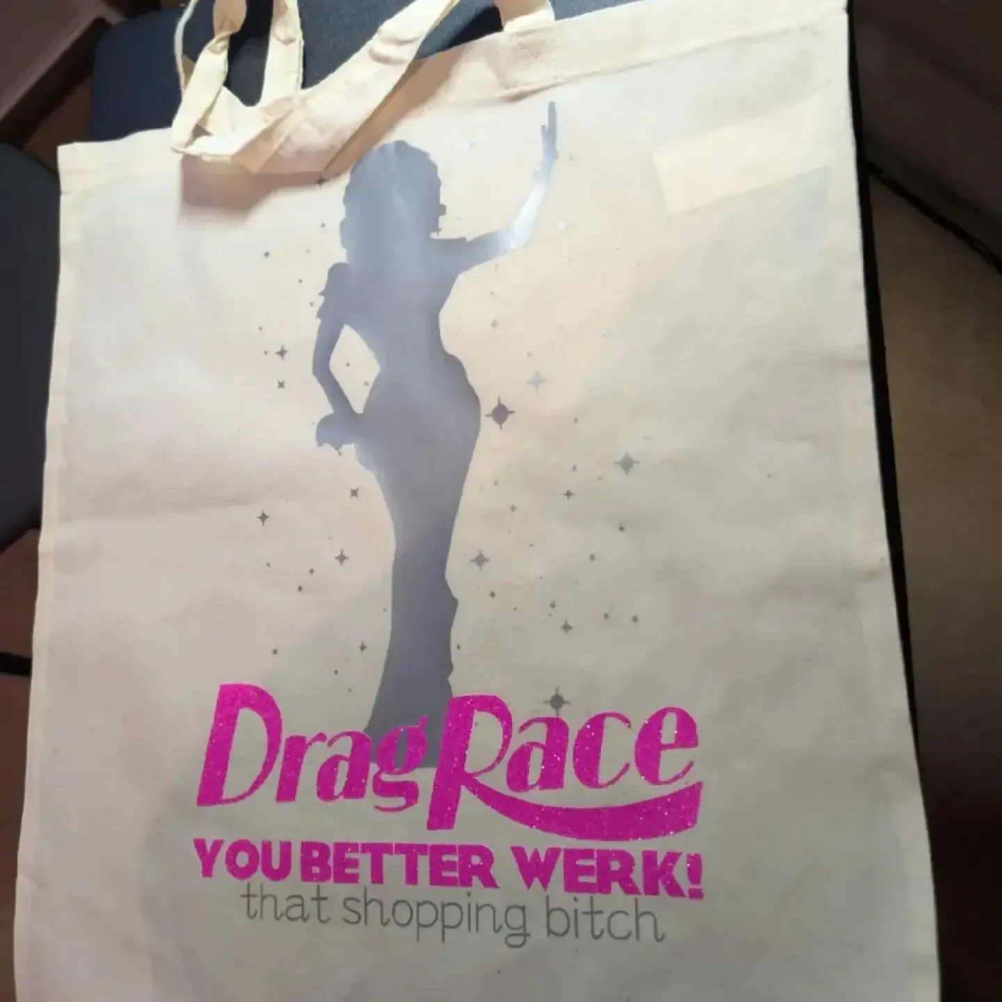 Cream tote bag with a silver dancer silhouette and bright pink custom Drag Race lettering
